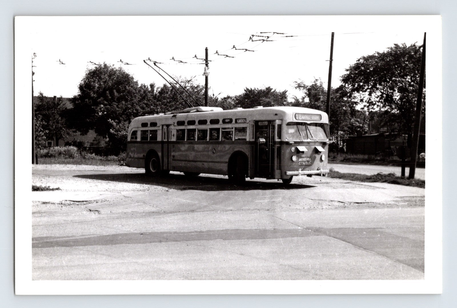 Chicago Surface Lines trolley bus 374 on Montrose route turning at intersection with overhead wires visible, black and white transit photo circa 1950s