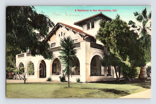 Vintage postcard of a residence in San Bernardino, California with trees and greenery.