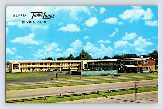 1960s chrome postcard of Travelodge motel in Elyria Ohio showing roadside motor lodge with parking area swimming pool and multi-unit guest buildings