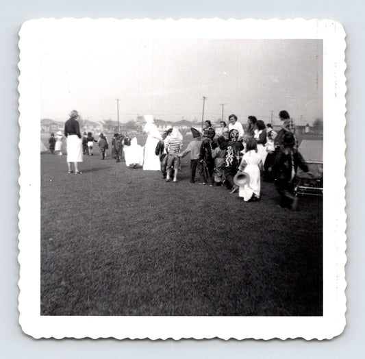 Children Halloween costume parade outdoor field line of kids masks 1953 snapshot