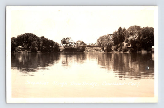 Sepia real photo postcard showing the drawbridge over Steamboat Slough at Courtland, California, with calm river reflections and trees lining the banks; postmarked 1952.