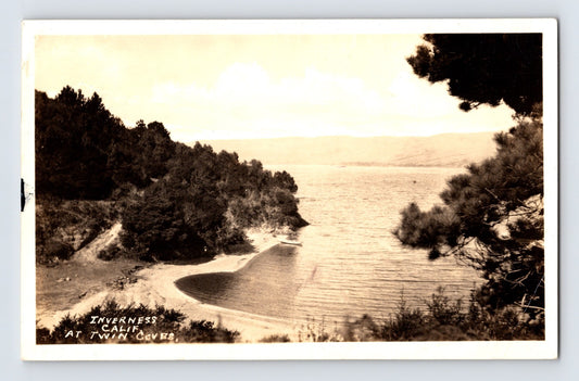 Sepia waterfront view of Twin Coves shoreline at Inverness California with curved beach and pine trees 1930s RPPC