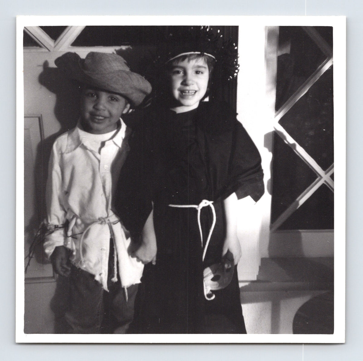 Children Halloween costumes scarecrow and witch holding hands indoors 1960s snapshot photo