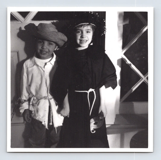 Children Halloween costumes scarecrow and witch holding hands indoors 1960s snapshot photo