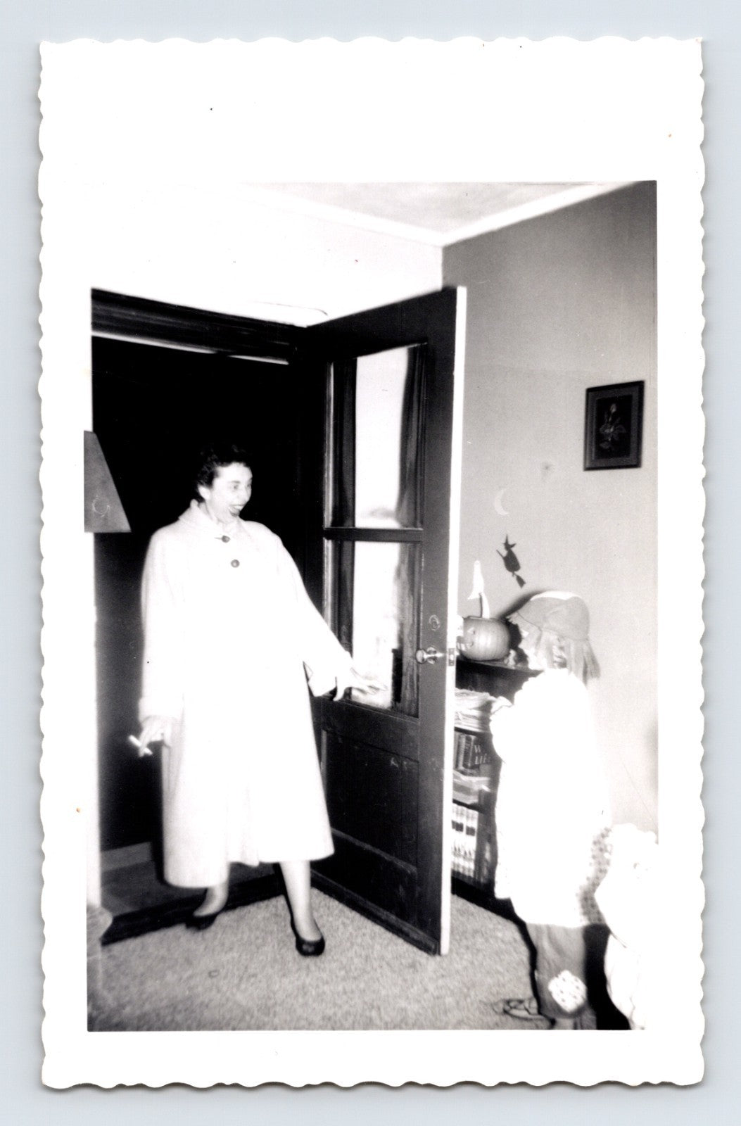 Halloween trick or treat child at front door woman answering pumpkin decoration indoor 1950s snapshot