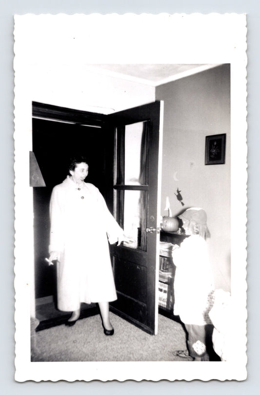 Halloween trick or treat child at front door woman answering pumpkin decoration indoor 1950s snapshot