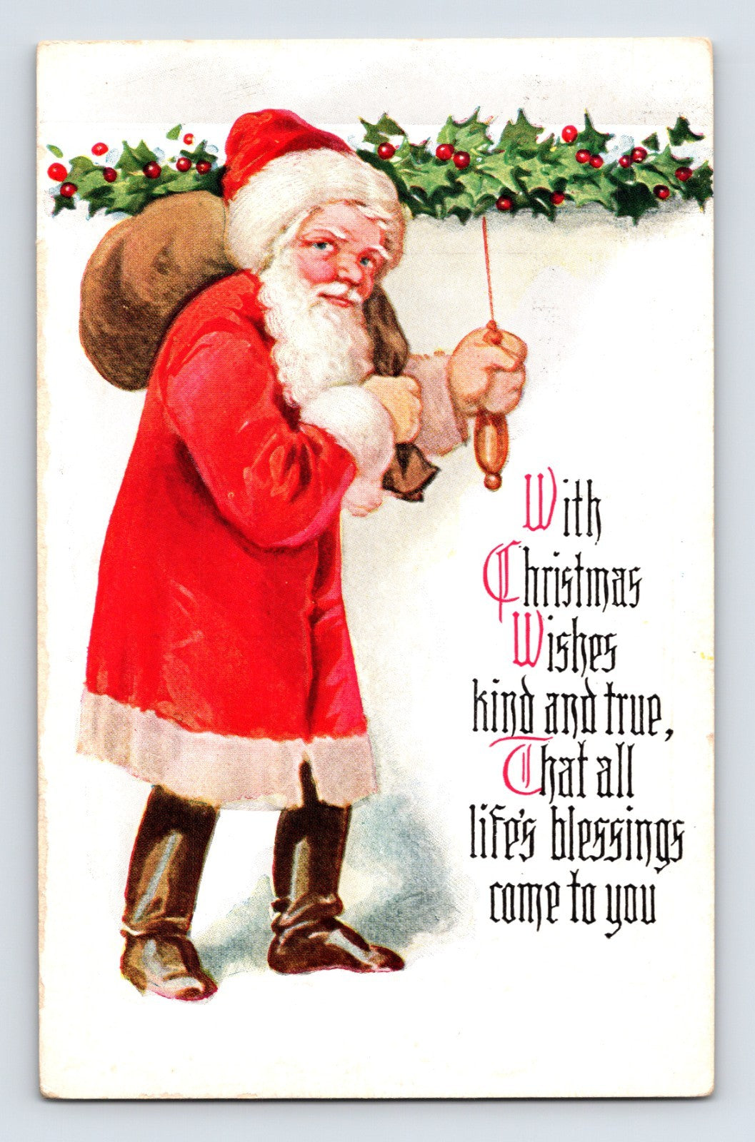 Santa Claus holding a hanging ornament beneath a holly garland beside blackletter Christmas verse on this early 1900s holiday postcard.
