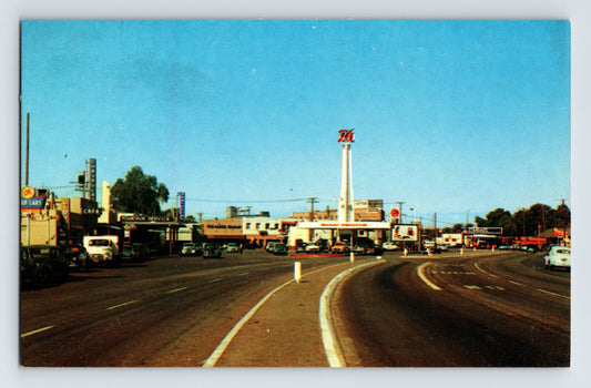 Highway 99 in Indio California showing Union Oil 76 gas station with tall 76 sign, curved roadway, and 1960s automobiles including Volkswagen