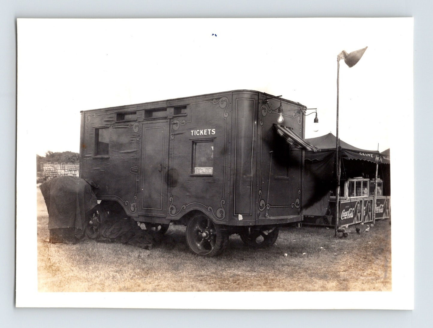 Black and white photograph of Cole Bros Circus ticket wagon with tickets window and adjacent Coca Cola stand under tent awning